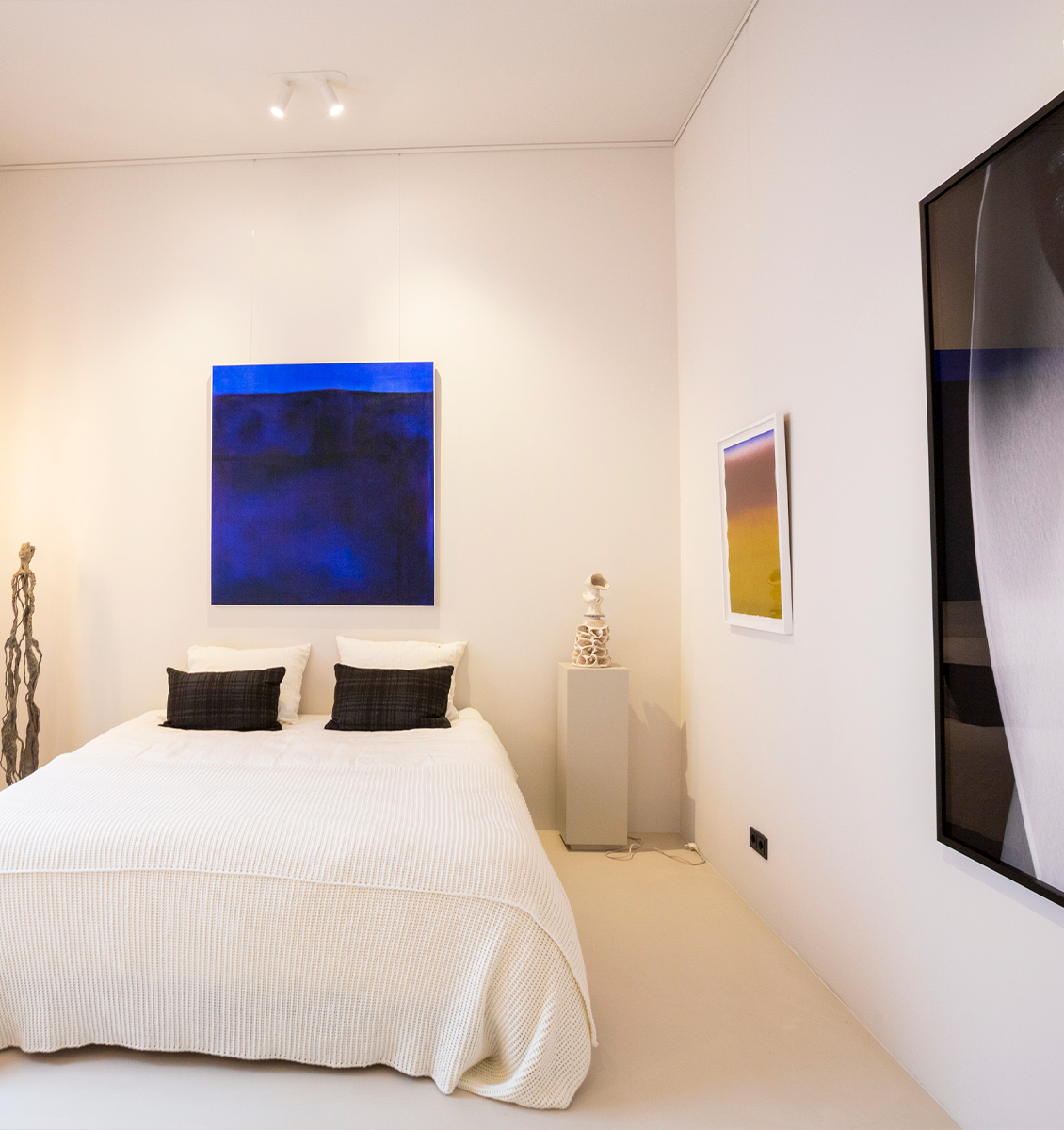 NL slaapkamer met kunstwerken aan muur groot blauw schilderij