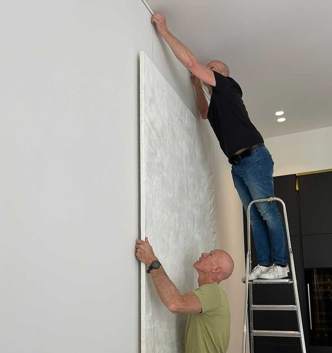 NL twee mannen op trap die groot schilderij hangen