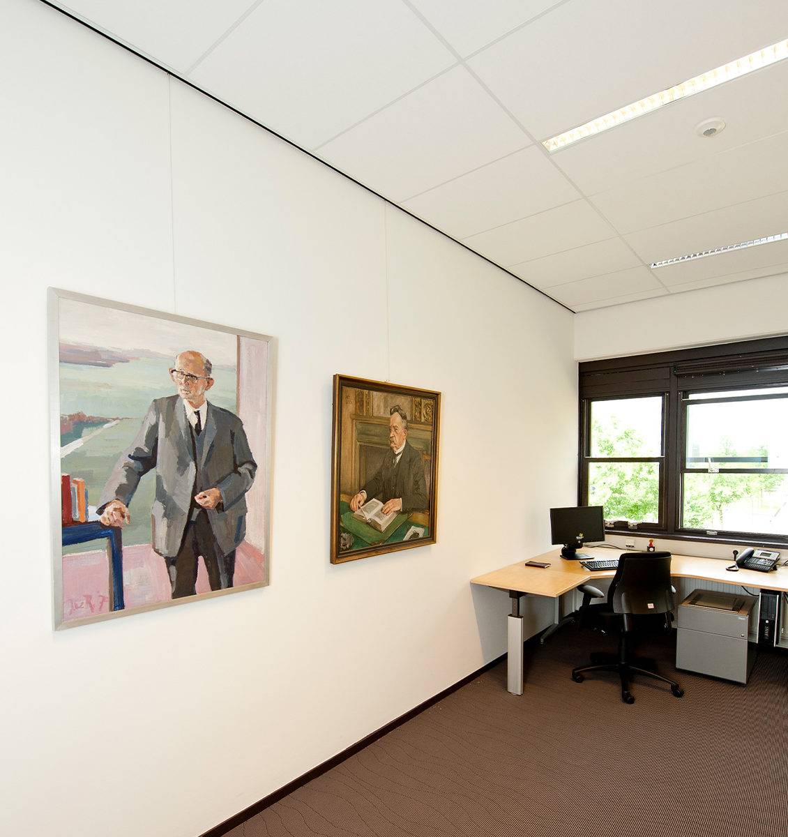 NL kantoorruimte in kantoorgebouw twee grote schilderijen van mannen