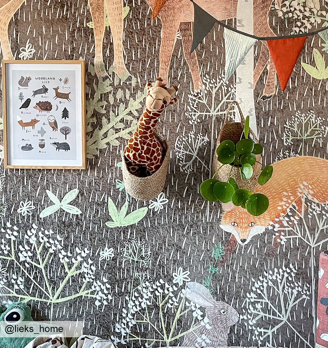 NL kinderkamer met poster van jungle dieren, giraffe knuffel en plantje aan de muur