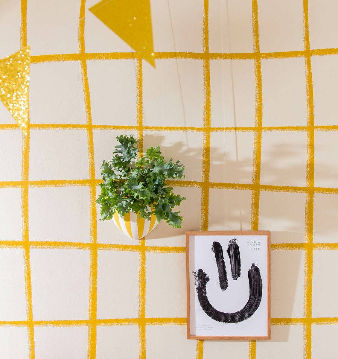NL gebokt behang aan de wand met daarop gehangen een Botaniq hangbloempot en een smiley poster